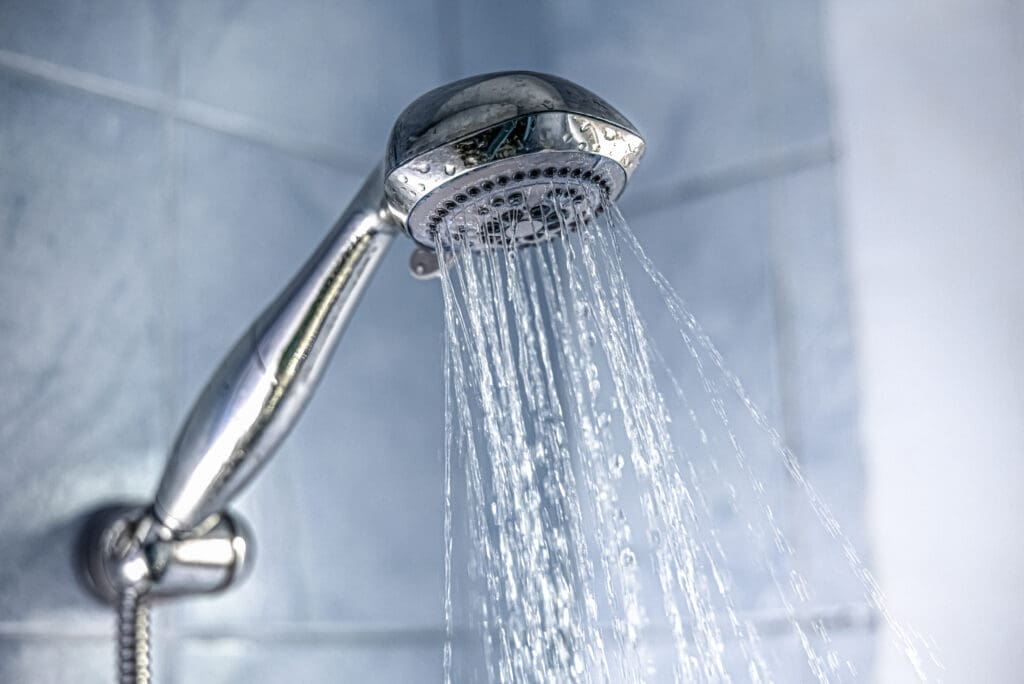 Closeup of a silver shower head splashing water in the bathroom